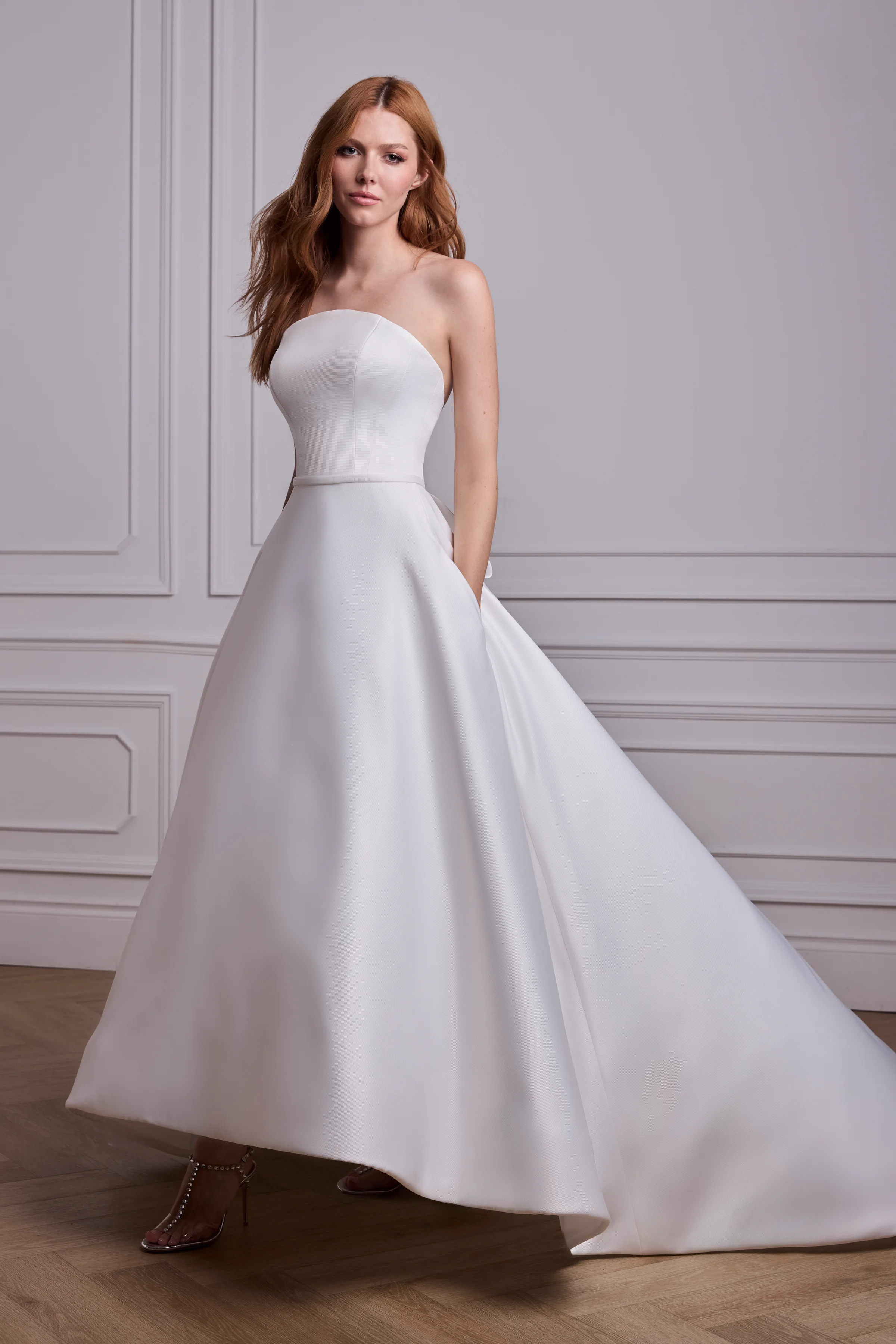 Strapless Satin Faille gown with an arched neckline, fabric band at waist, and a high-low circle skirt.