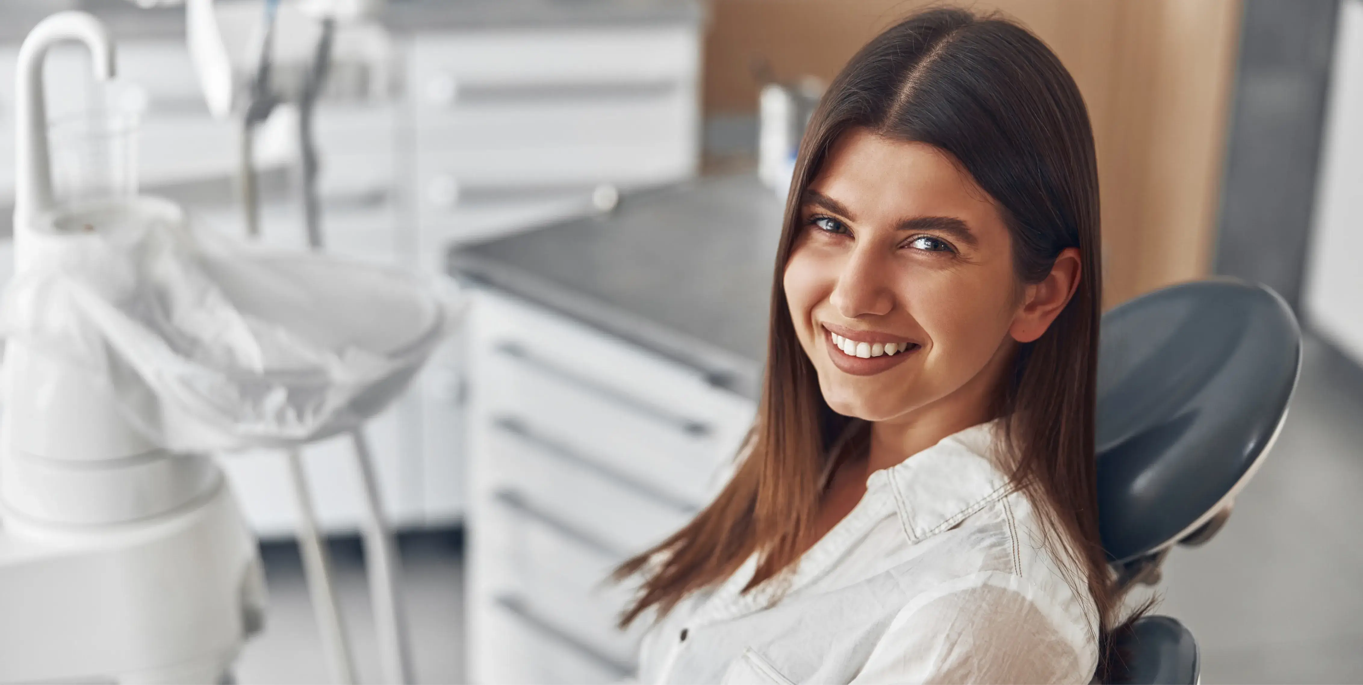 A woman sitting in a dentist chair smiling.