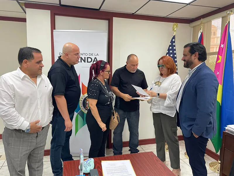Secretary of the Department of Housing William Rodríguez and Regional Director of Housing in Aguadilla, presenting property titles and vouchers to two families.