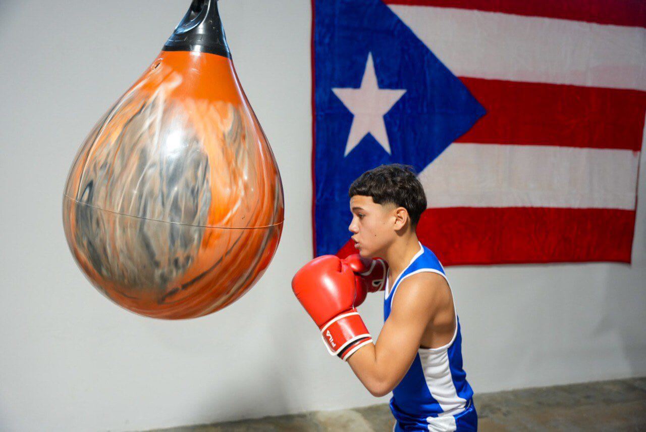 Joven boxeador frente a saco de arena.
