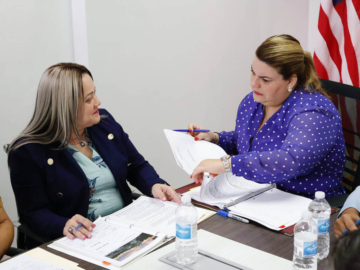 Jenniffer González Colón y Ciary Pérez Peña hablando con documentos en mano.