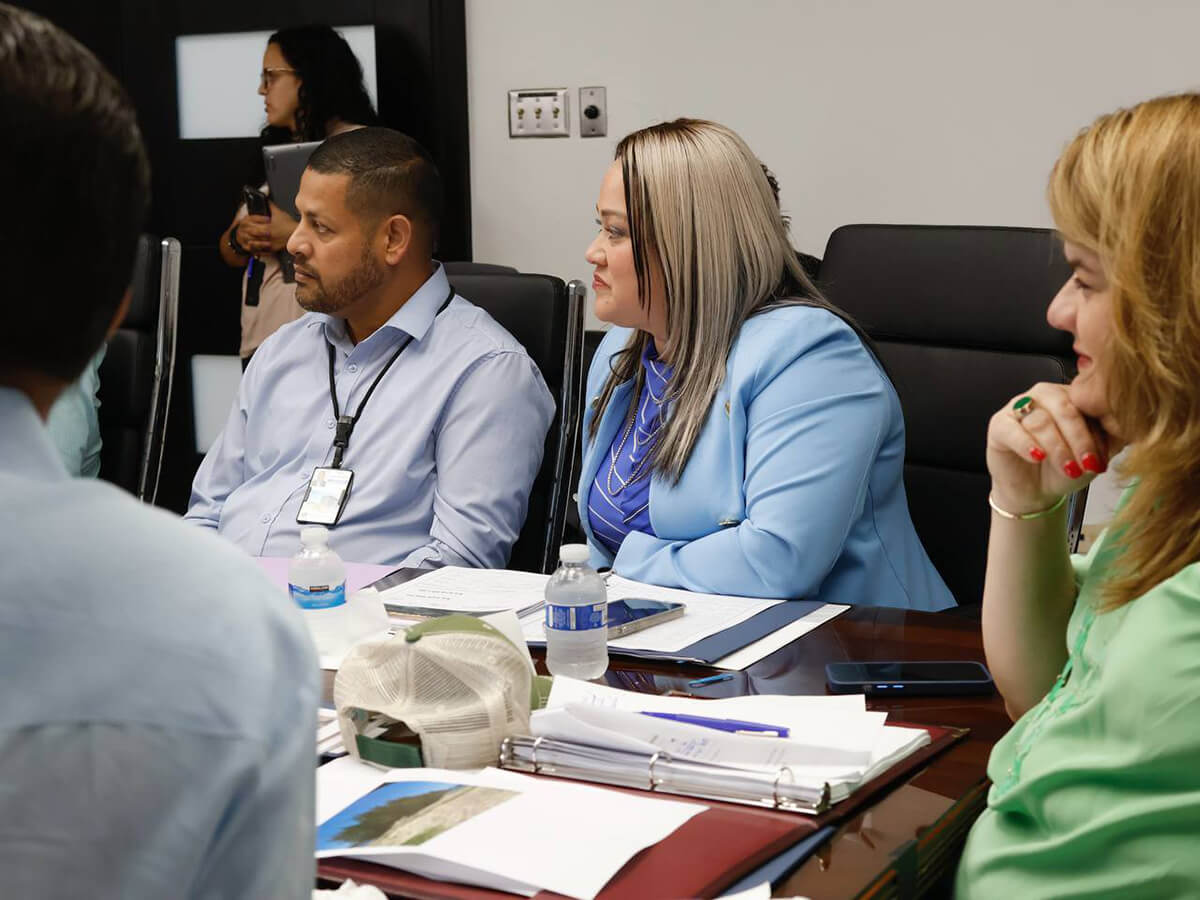 Ciary Pérez Peña y Jenniffer González Colón junto a un funcionario, atendiendo la reunion.