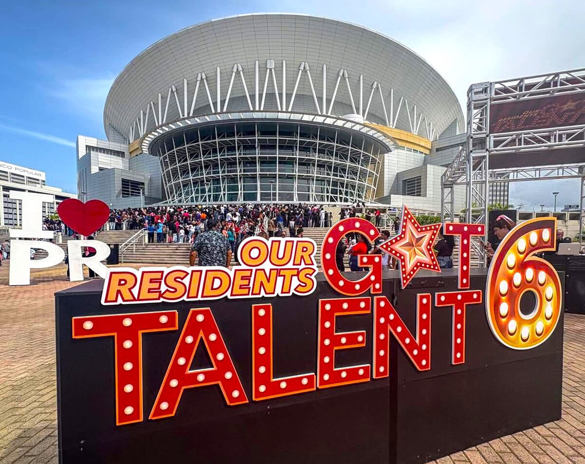 Photo in front of the José Miguel Agrelot Coliseum in Hato Rey and the Our Resident Got Talent sign.