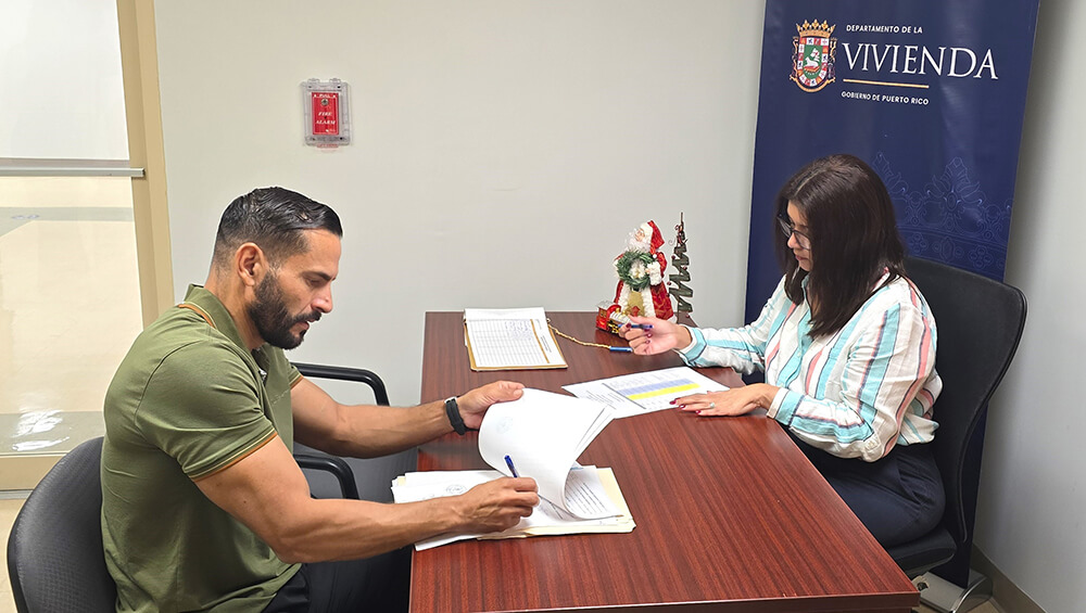 Sra. Michelle Díaz Navedo y junto a uno de los compradores, firmando documento.