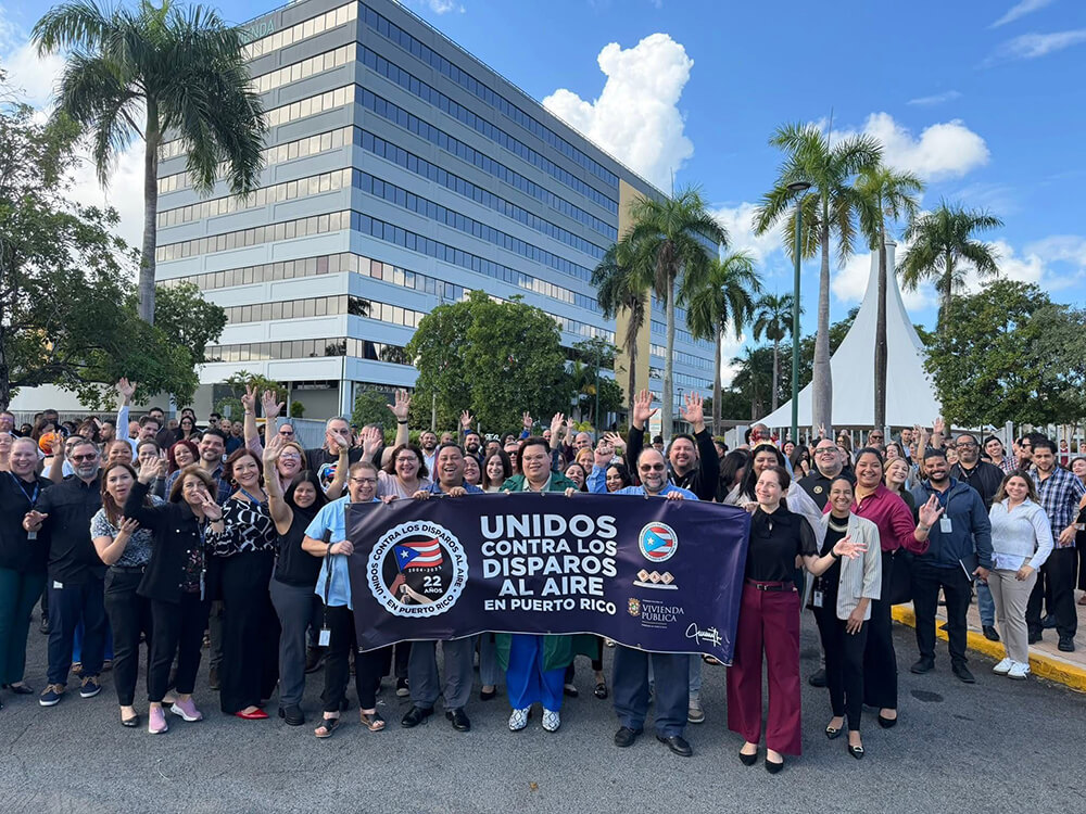 Multitud de personas sosteniendo letrero que dice Unidos contra los disparos al aire en Puerto Rico.