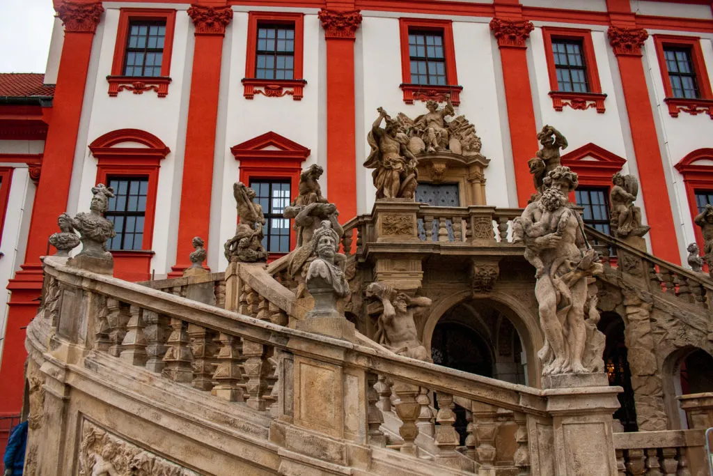 Baroque Troja Chateau with grand staircase and statues.