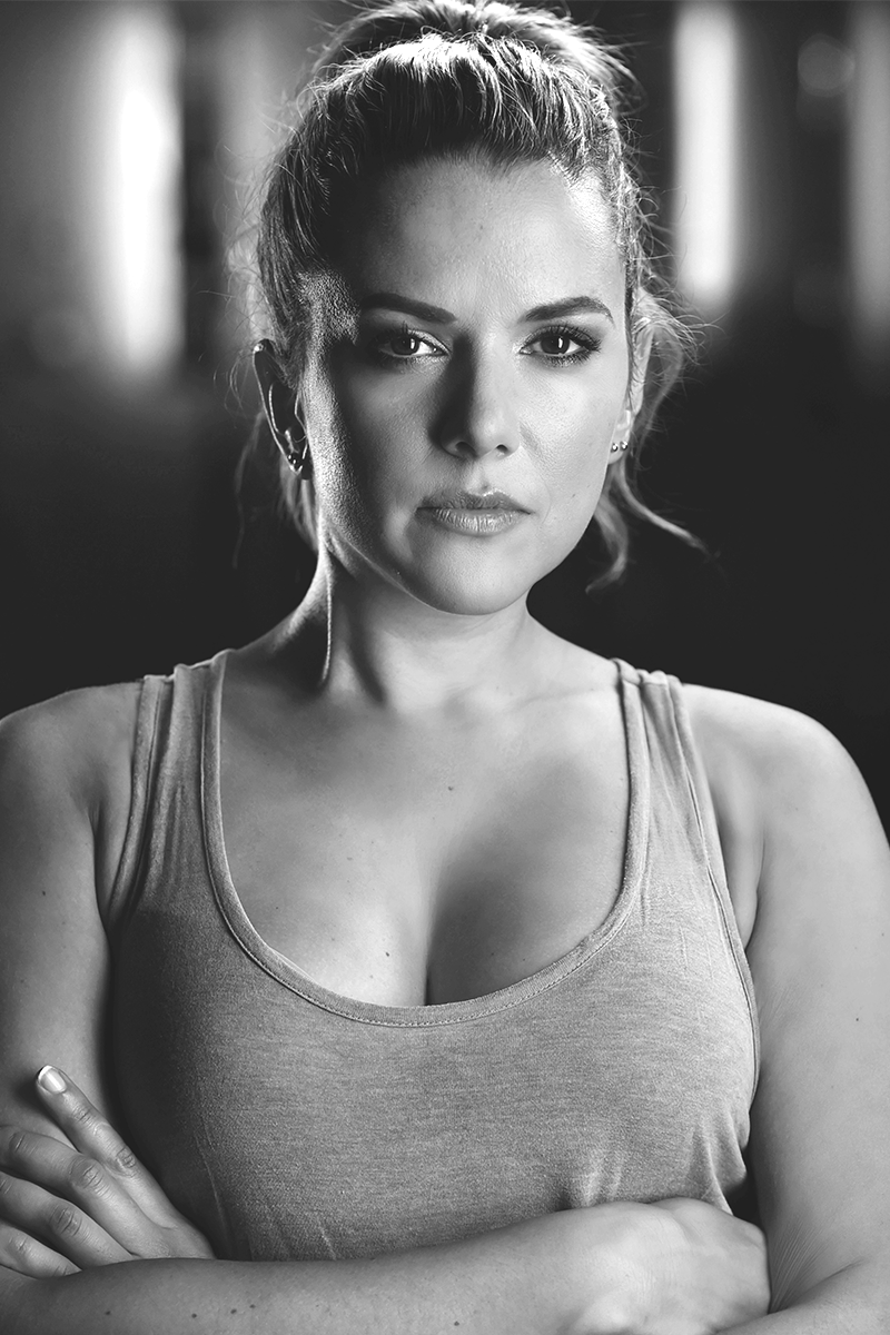 Portrait of Jennifer Moxham, Producer at Inspired Artists, looking confidently at the camera with arms crossed, wearing a tank top
