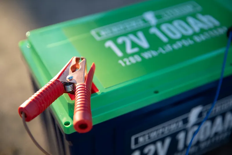 Red battery clamp attached to a 12V power inverter, highlighting electrical connections, portable power equipment, and energy conversion.