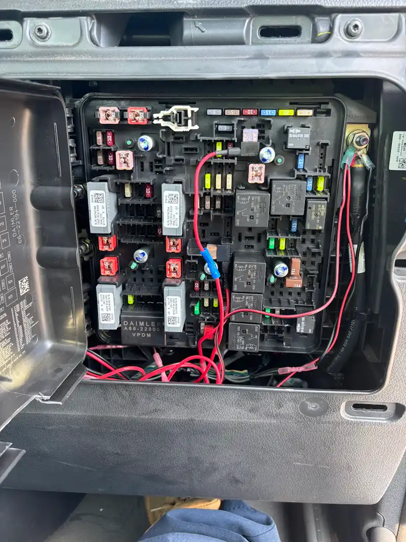 Electrical diagnostics on a semi-truck fuse panel with relays, fuses, and test wiring during troubleshooting. The fuse panel is labeled "DAIMLER."