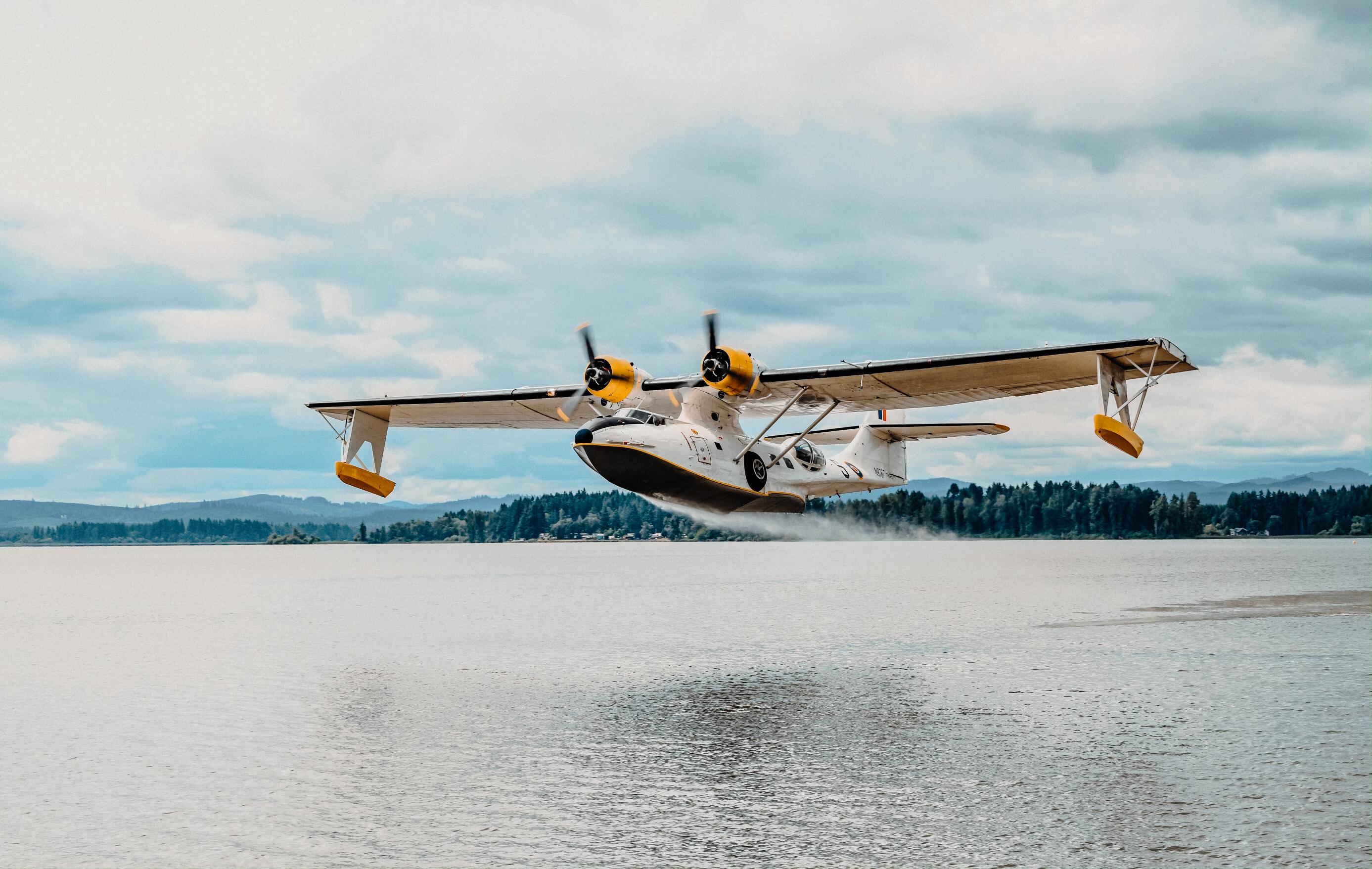 Soaring by the Sea's 1943 PBY-5A Catalina fixed wing aircraft flying over a lake