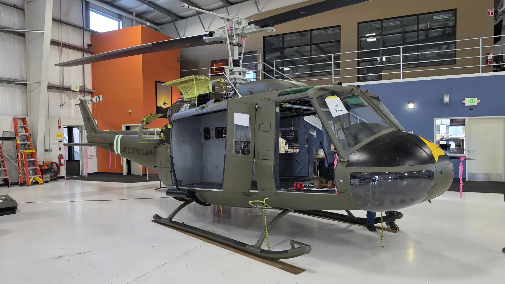 United States Army helicopter inside a hangar undergoing maintenance with open panels.