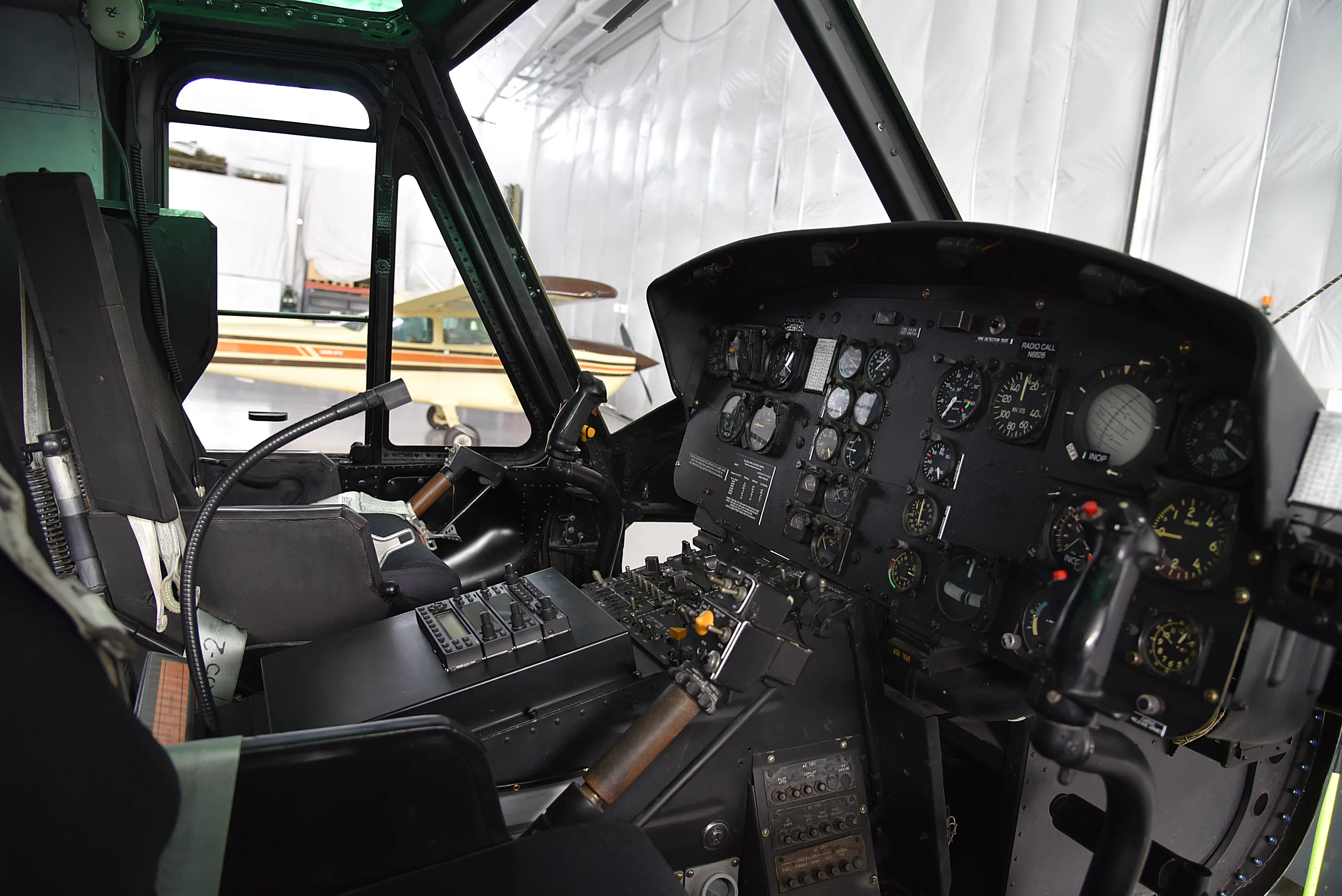 Cockpit of a vintage aircraft featuring various analog gauges, dials, switches, and a control stick.