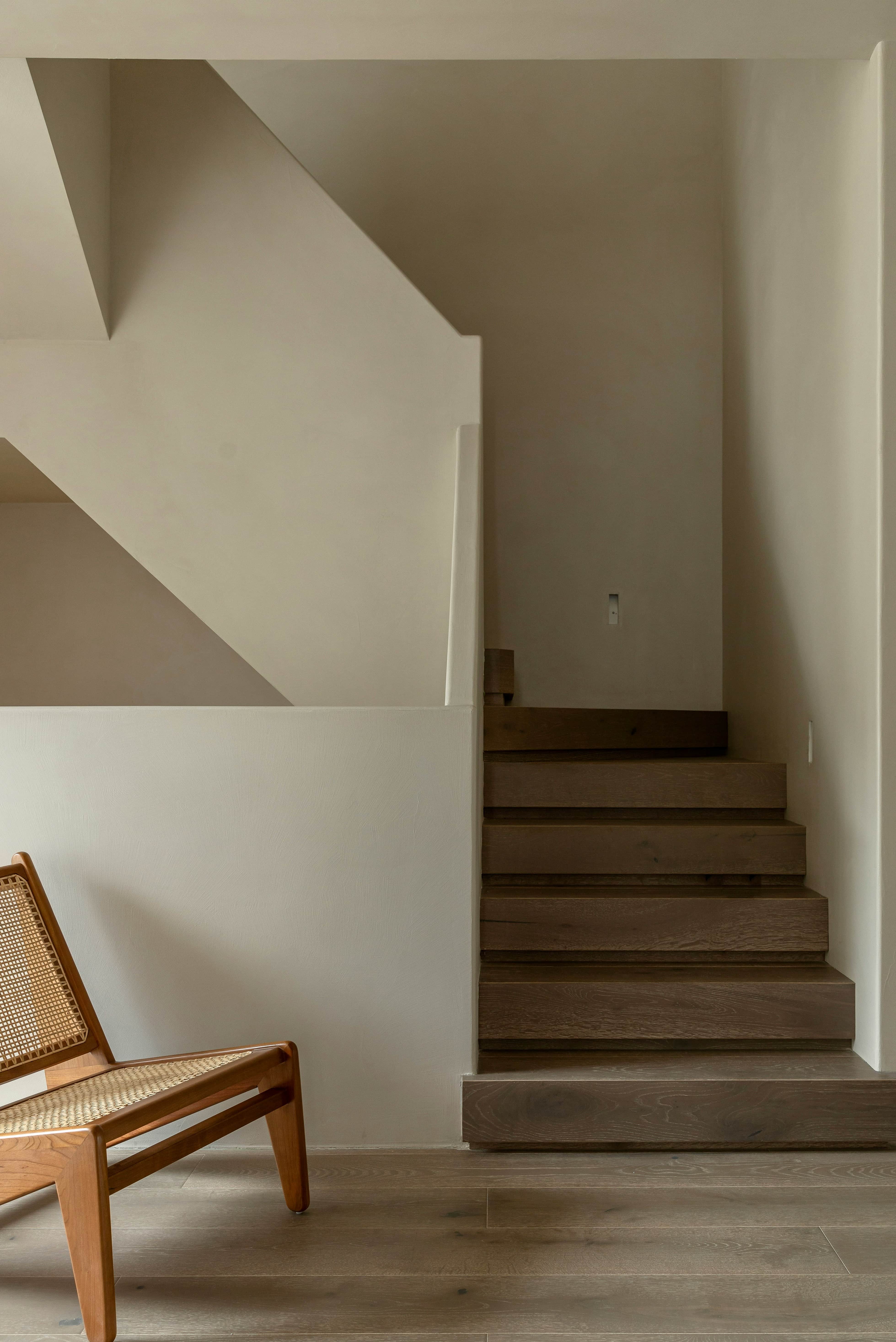 A wooden chair is sitting in front of a white wall.
