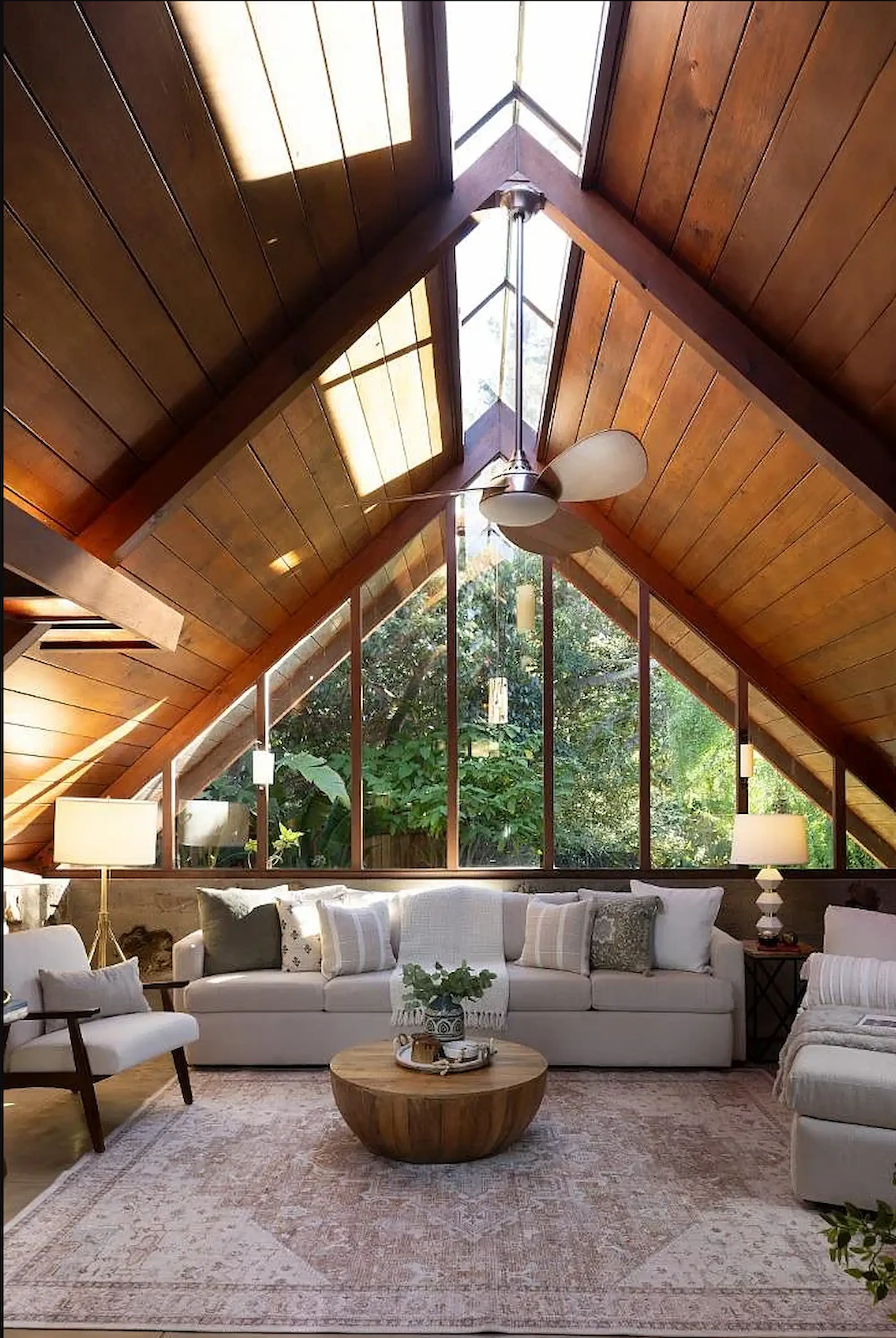 Mills house, Carmel Beach, CA showing the interior of the home looking out of the triangle shaped peaked ceilings looking out the glass window and lush foliage