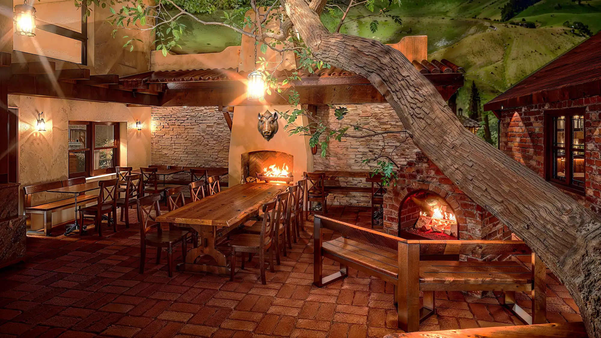 Hogsbreath Inn, Carmel-by-the-Sea, CA realistic rendering showing the outdoor patio during the nighttime with several lit fireplaces and seating tables with live edge wood tables designed by Julia Correia