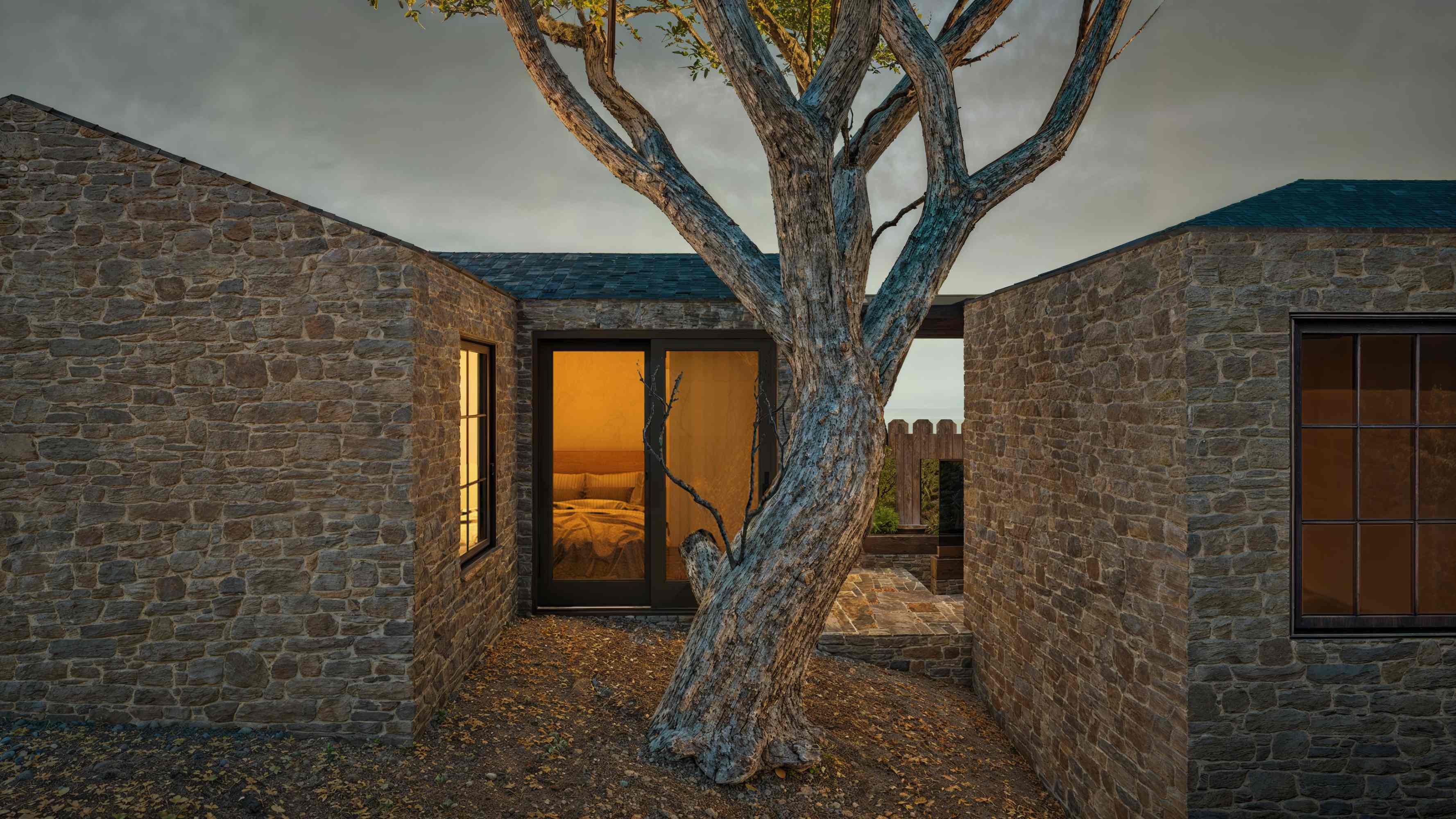 Dusk rendering of the Jeffers Cabin addition glowing around the protected live oak
