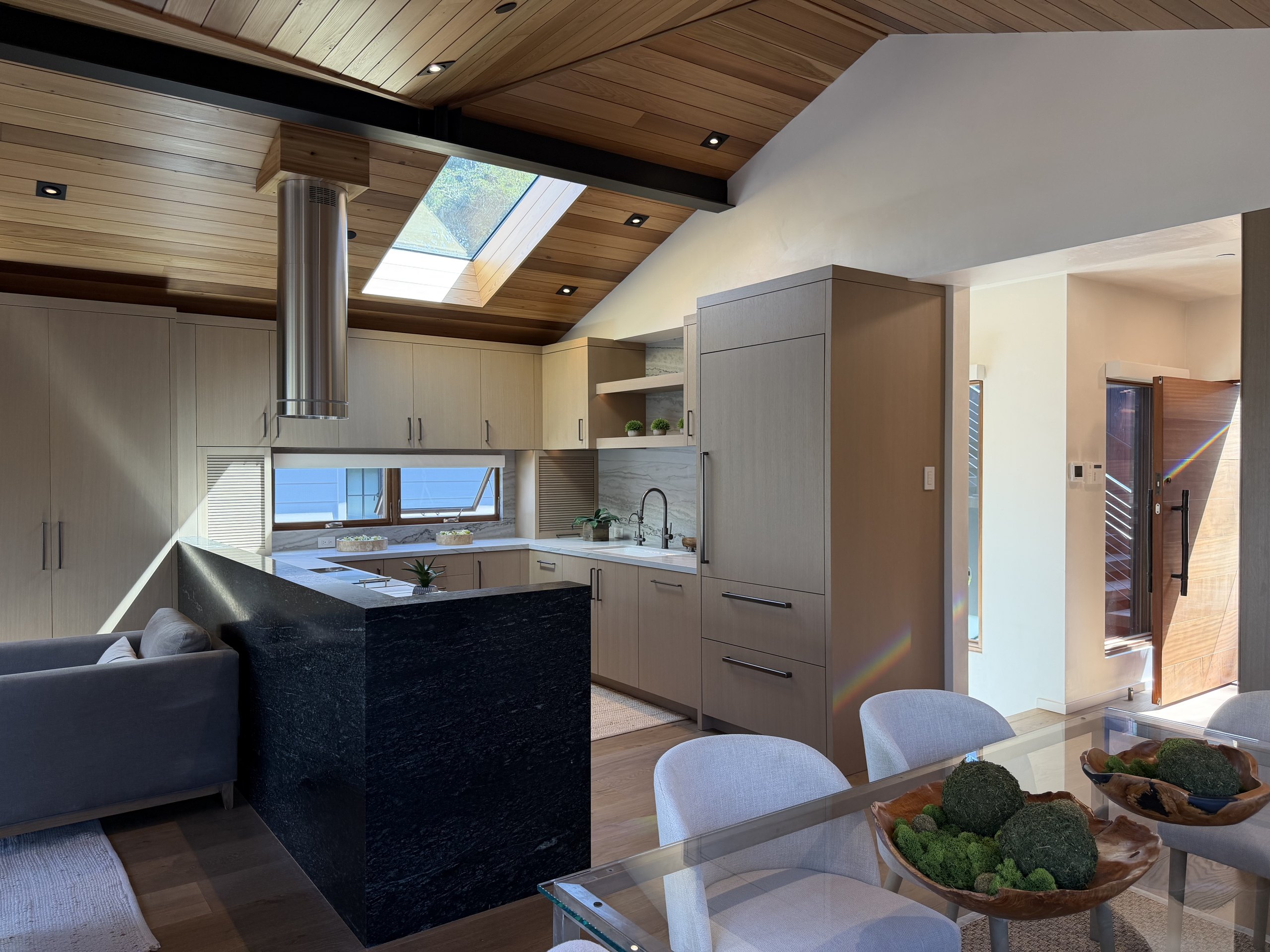 Brisa kitchen with skylight, dark stone island, and view to the entry