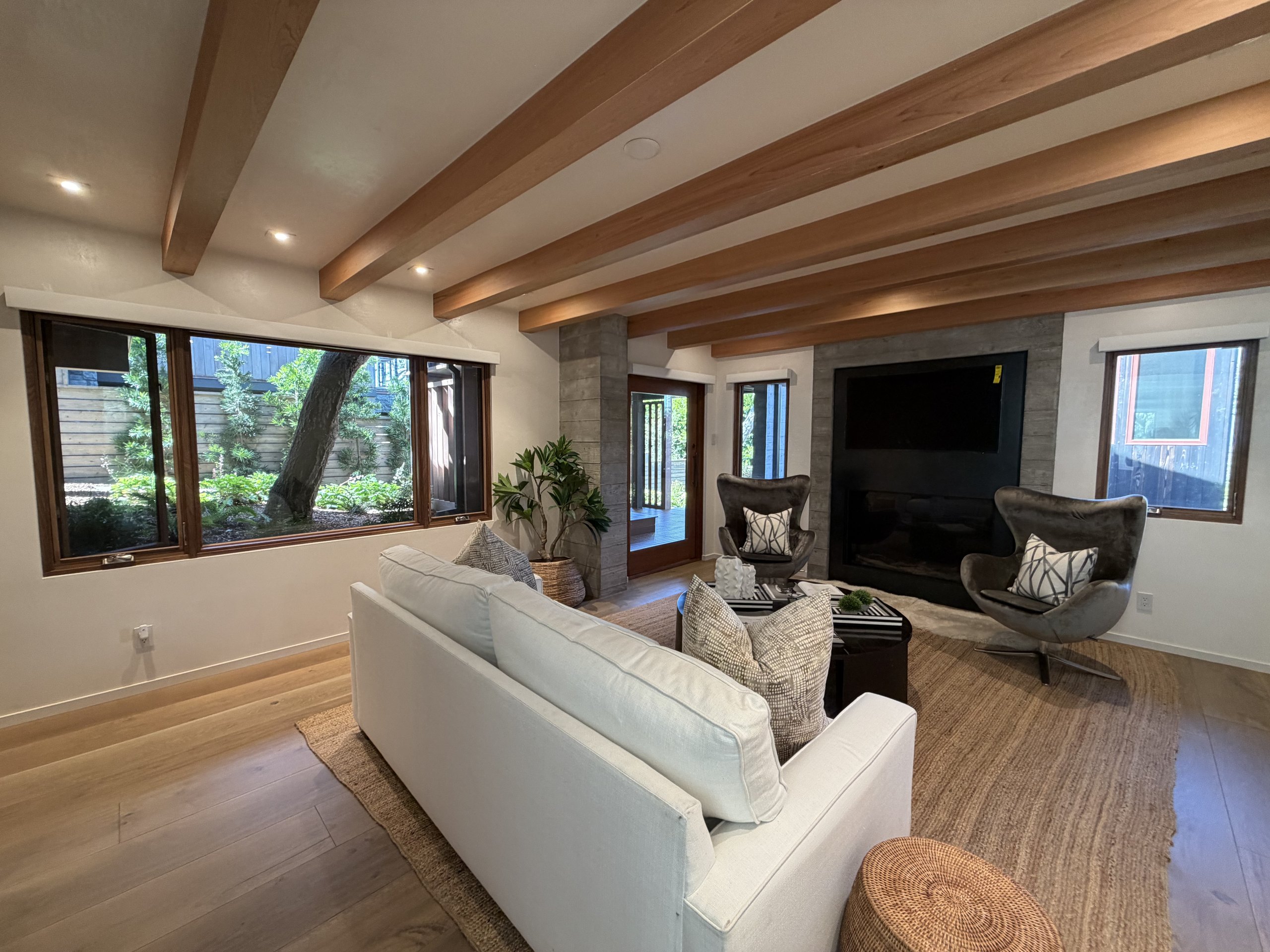 Family room at Brisa with exposed beams, garden window, and board-formed concrete fireplace