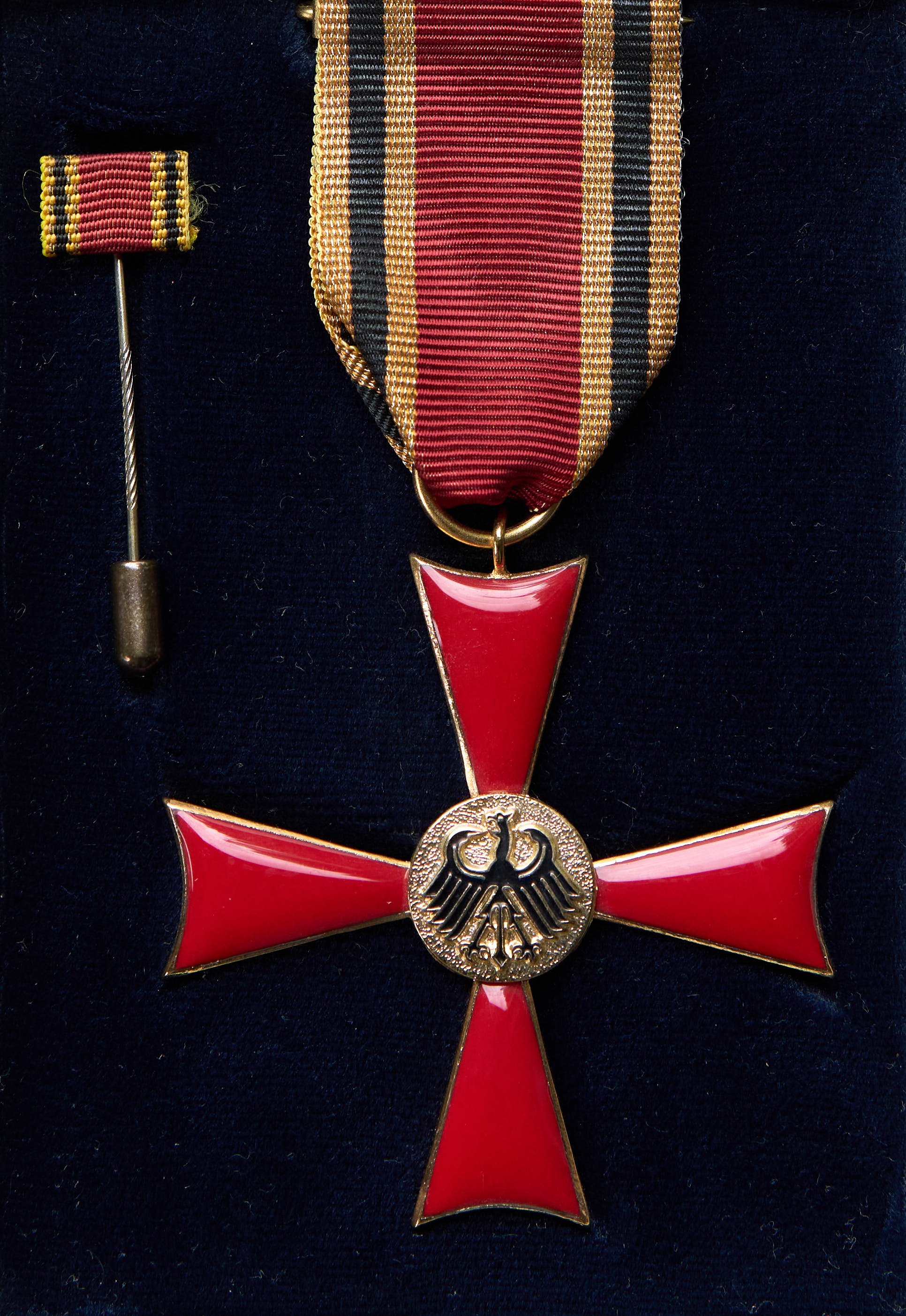 Rotes Kreuz mit goldenem Adler in der Mitte und rot-schwarz-gold gestreiftem Band auf dunkelblauem Hintergrund.