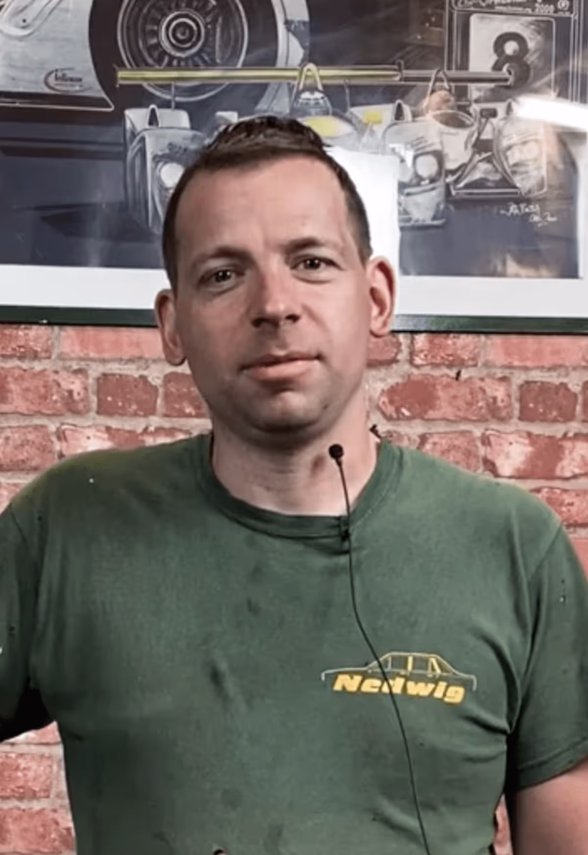 Mann im grünen Shirt vor Backsteinwand – zufriedener Immobilienkunde berichtet