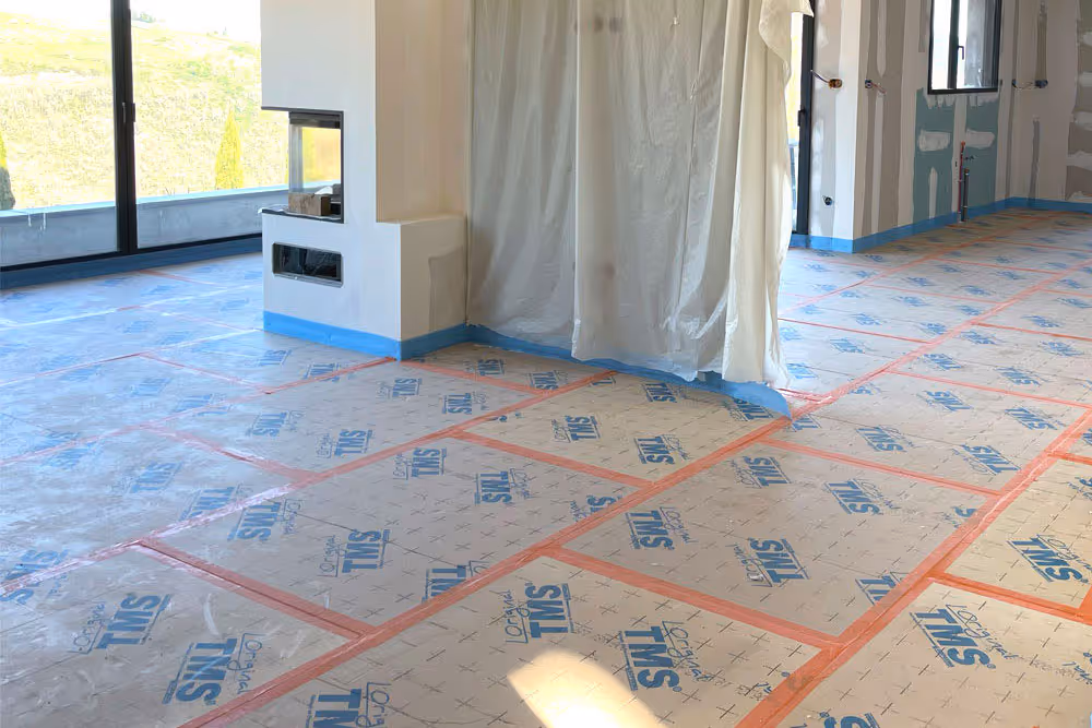 Pose d'isolant thermique et phonique au sol dans une maison en construction, préparatif avant application de chape fluide par Lead Chapes, spécialiste de la chape fluide et de l'isolation des sols.
