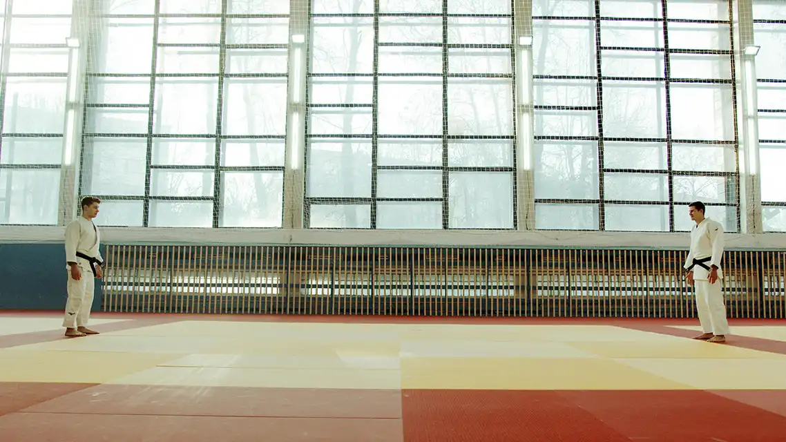 Two martial artists preparing to spar on a tatami mat, illustrating a side-by-side comparison — similar to evaluating GIF versus HTML5 banner formats.