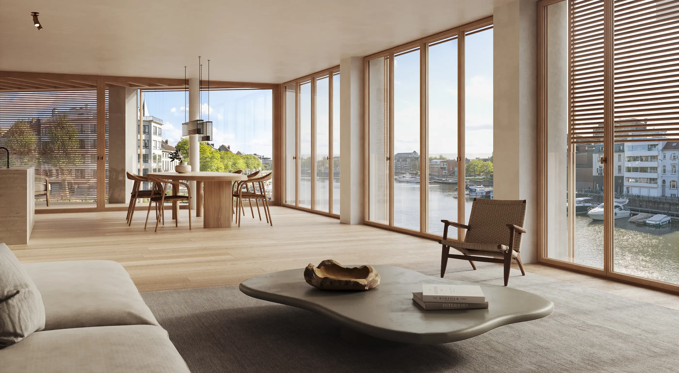 Moderne woon- en eetkamer met grote ramen en uitzicht op de waterkant, minimalistisch ingericht met een bank, salontafel, fauteuil en eettafel. Licht en ruimtelijk.