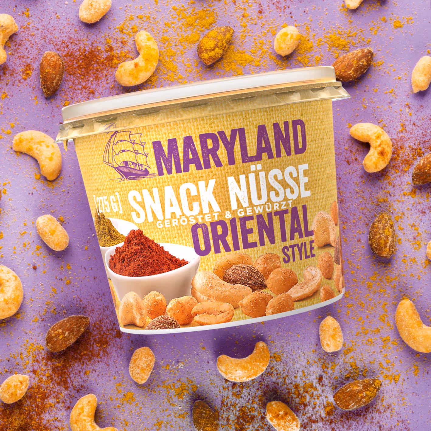 Container of Maryland Snack Nüsse Oriental Style roasted and spiced nuts with scattered nuts and spices on a purple background.