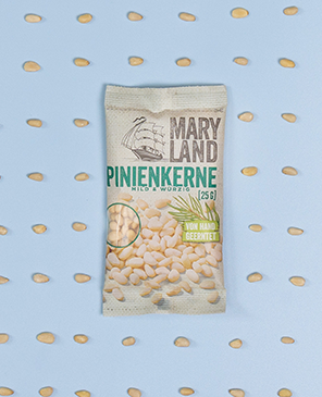 Packung Maryland Pinienkerne mit verstreuten Kernen auf blauem Hintergrund.