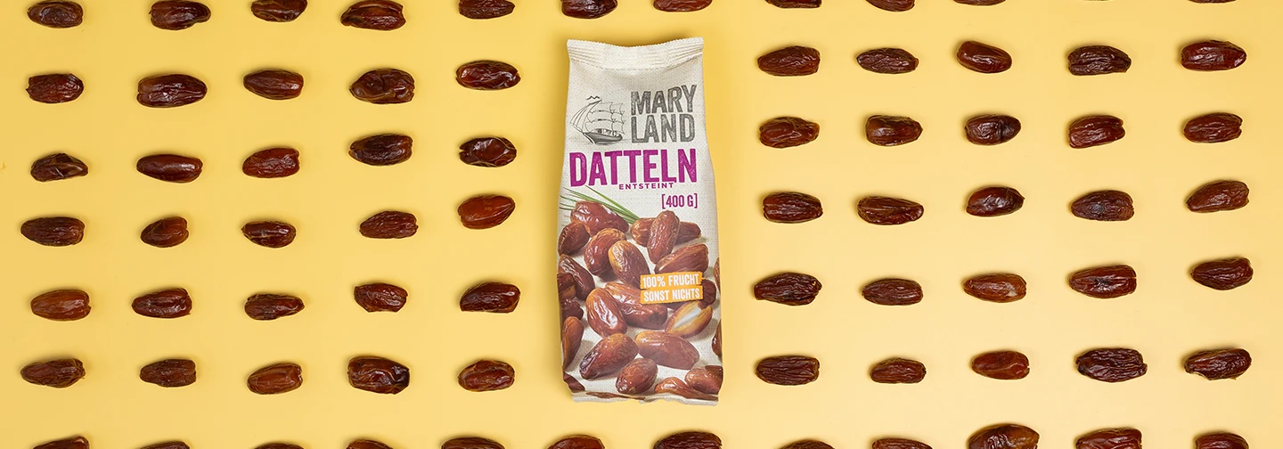 Eine Packung Maryland entsteinte Datteln (400 g) auf gelbem Hintergrund, umgeben von in Reihen angeordneten einzelnen Datteln.