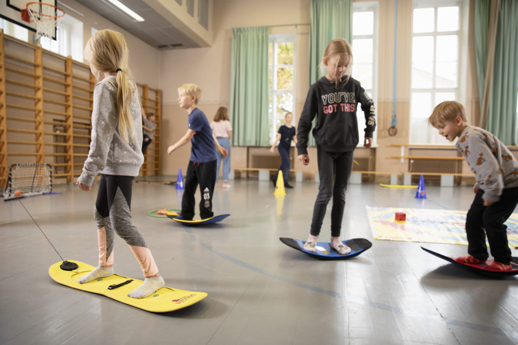 Kids training to balance on a snowboard indoor