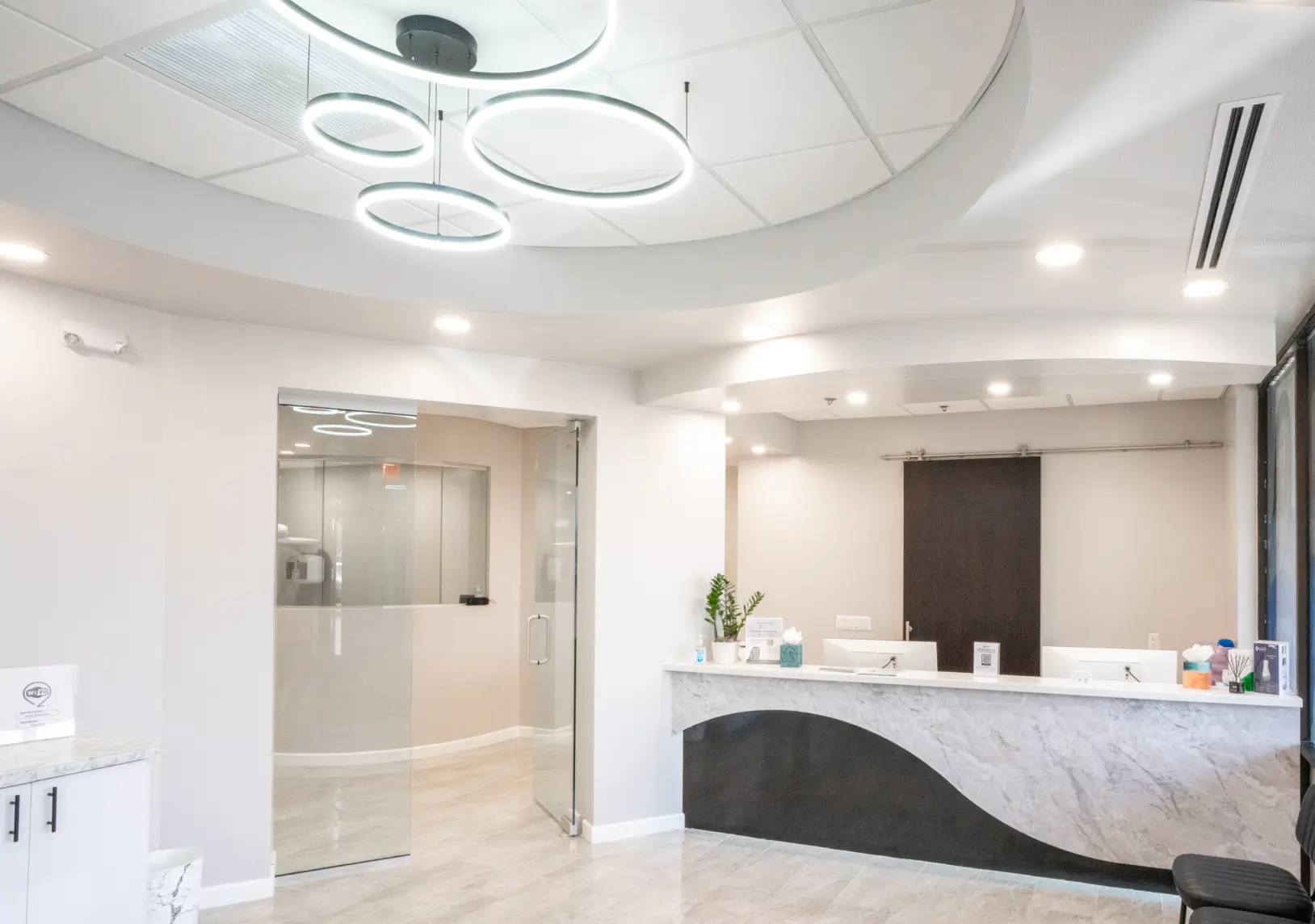 Empty modern reception area with a curved desk and decorative circular lights on the ceiling.