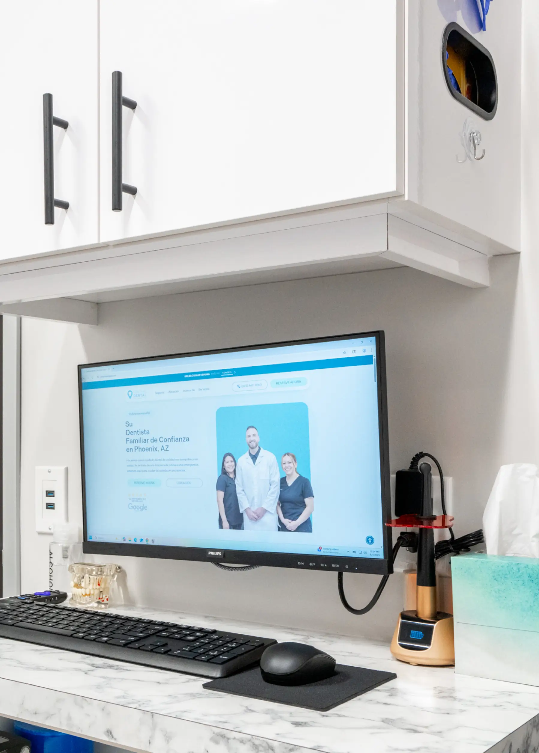 A computer monitor on a desk shows a website featuring three people in a group photo.