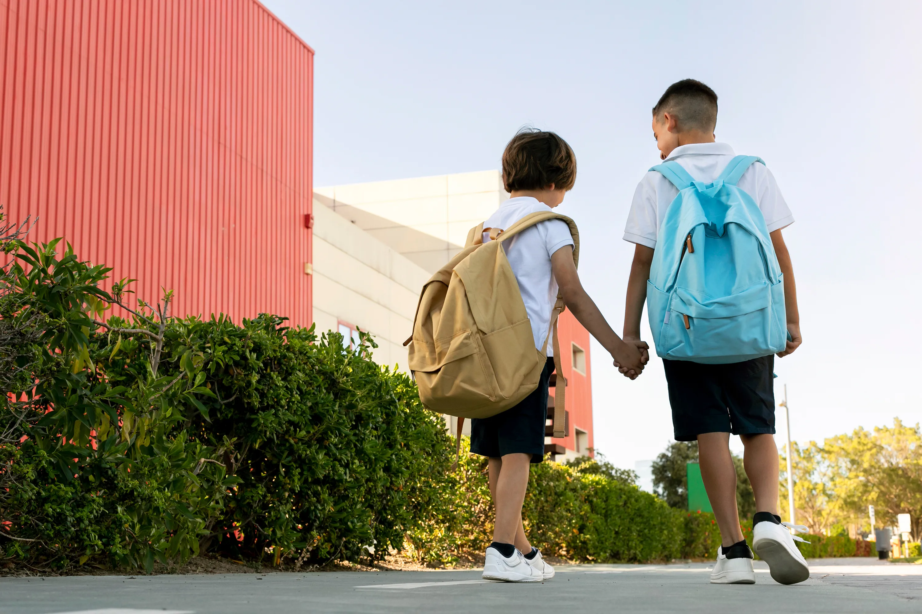 A boy and a girl holding hands walking down the street.