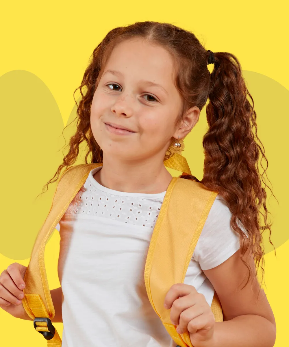 A little girl wearing a yellow backpack and smiling.