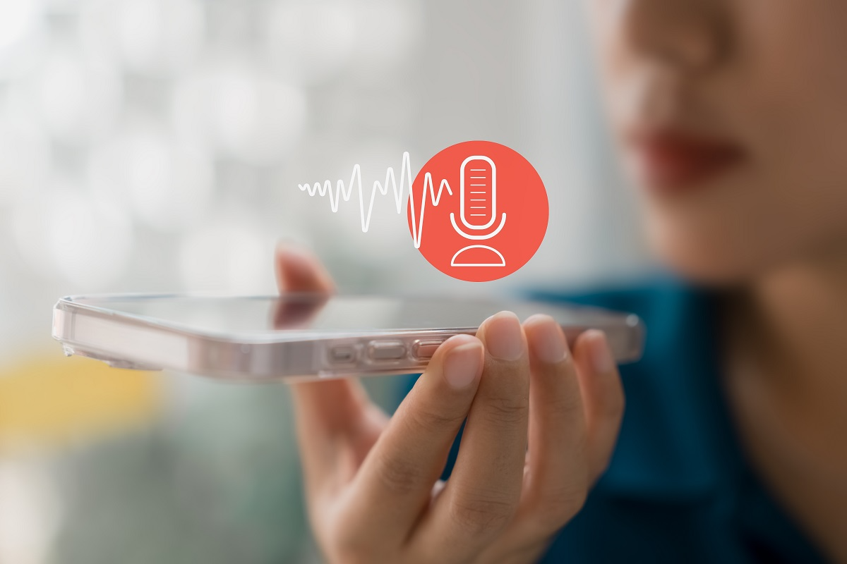 Person speaking into smartphone microphone with audio waveform, representing voice recognition or AI voice analysis