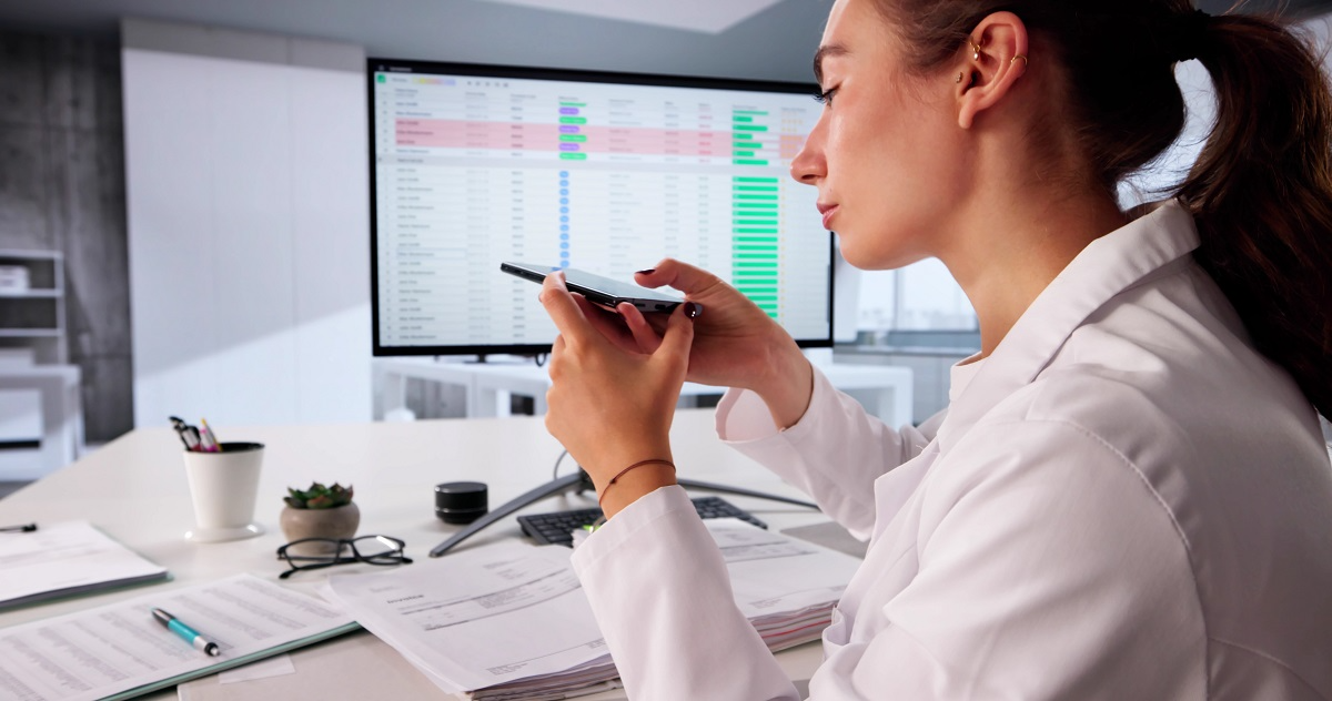 Healthcare professional reviewing fraud detection data on smartphone with analytics dashboard on screen