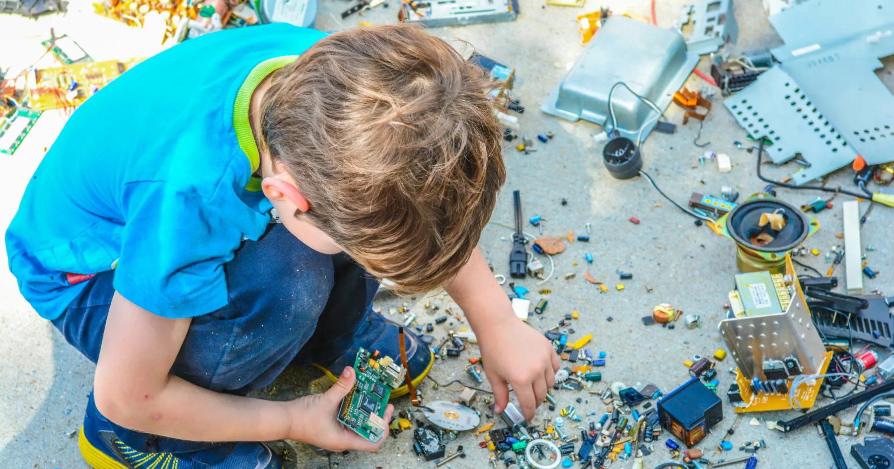 Boy sorting electronic components and circuit boards on the ground