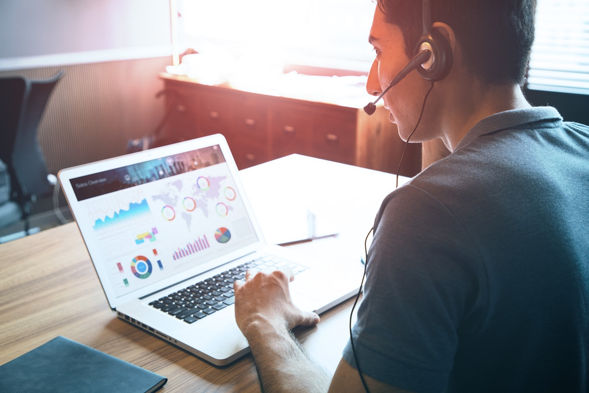 Customer service agent reviewing real-time call center analytics and performance dashboards on a laptop during a support call