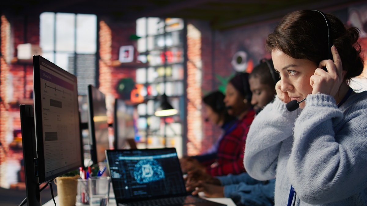 Contact center agent wearing a headset while monitoring customer calls, representing AI monitoring technology used for real-time risk detection, quality assurance, and agent support.