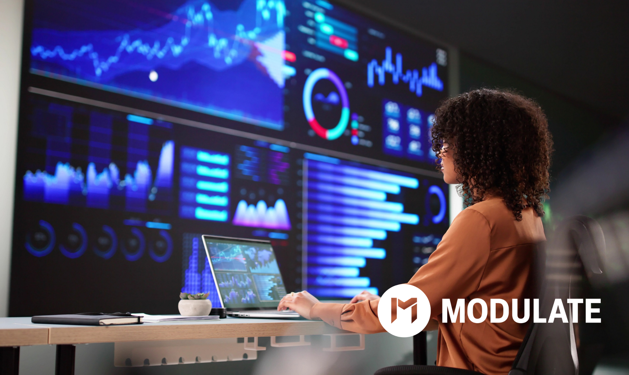 Analyst reviewing charts and performance trends on large call center analytics dashboards.