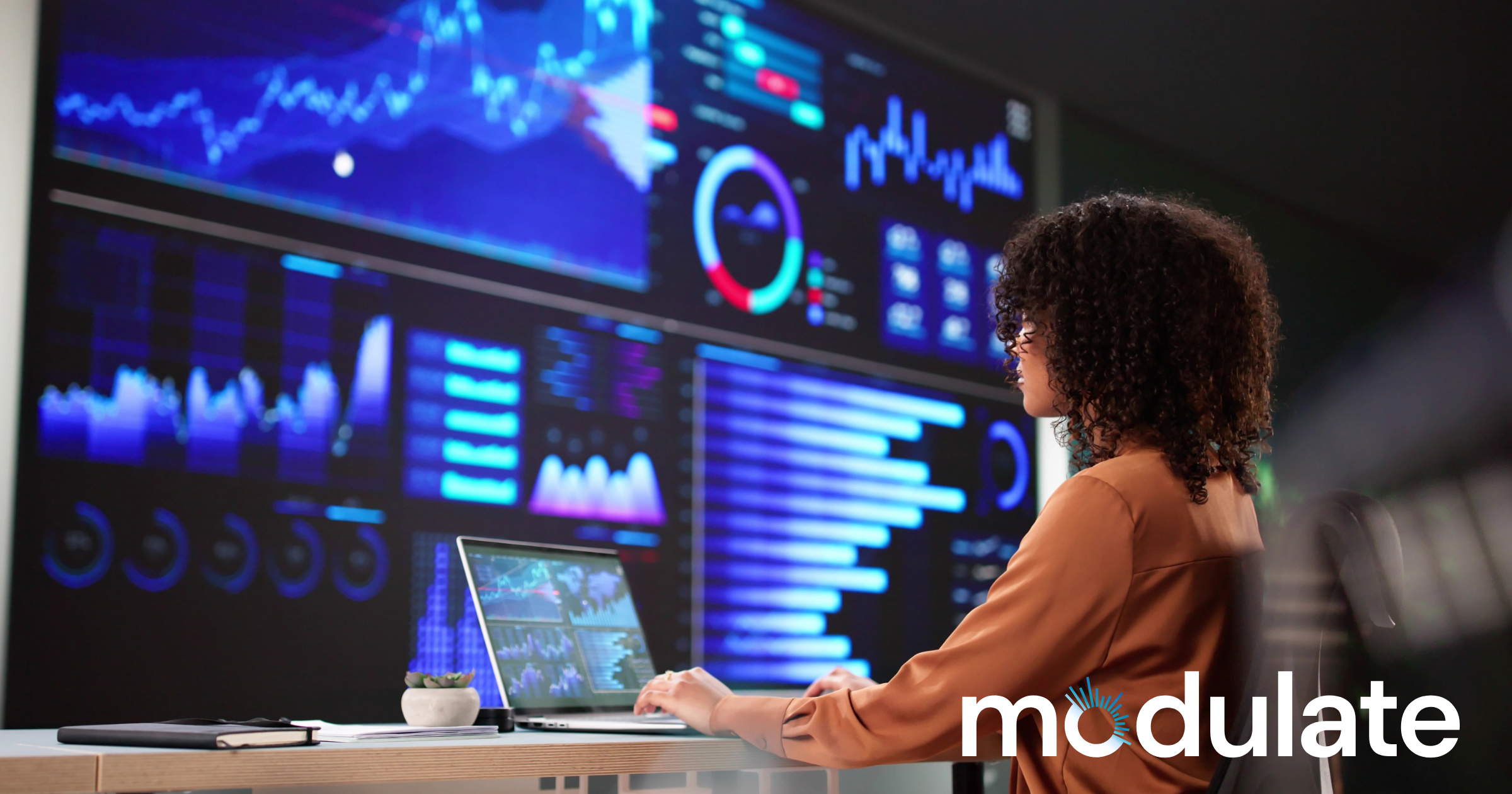 Analyst reviewing charts and performance trends on large call center analytics dashboards.