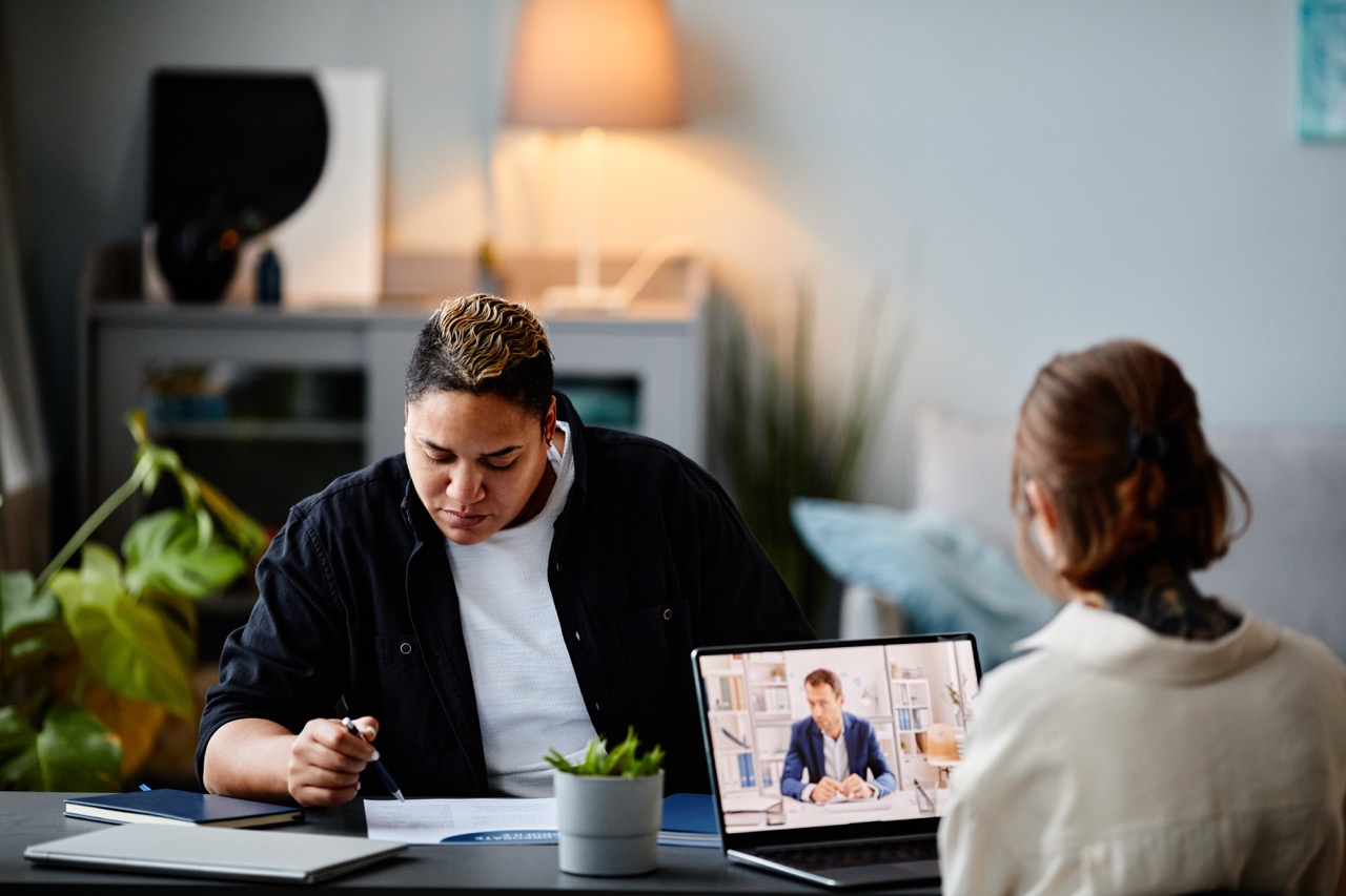 2 woman working and one of them in a meeting.