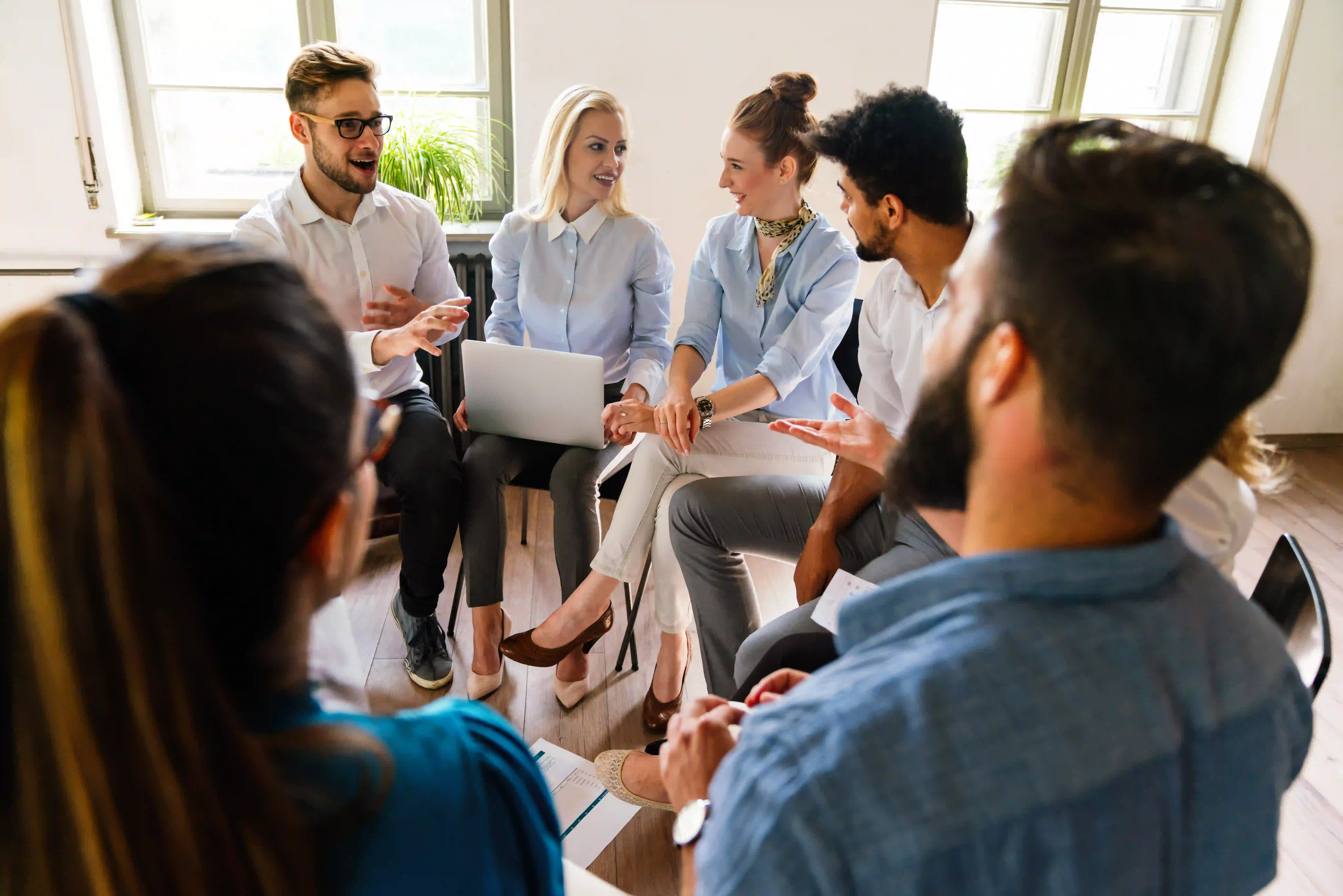 A diverse group of individuals engaged in conversation while seated around a table, fostering collaboration and connection.