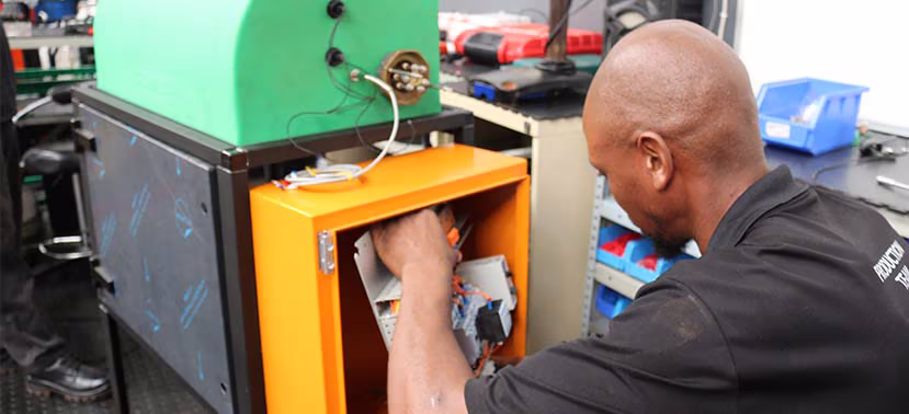 A man fixing the wiring on the electrical control panel of a high-pressure washer.