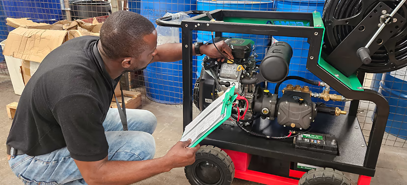 A man inspecting the engine of a high-pressure washer.