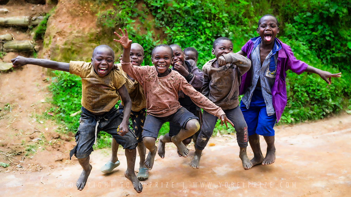 Excited Group of Children: A spirited group of Ugandan children jump and pose with excitement, their smiling faces and playful gestures showcasing their happiness.