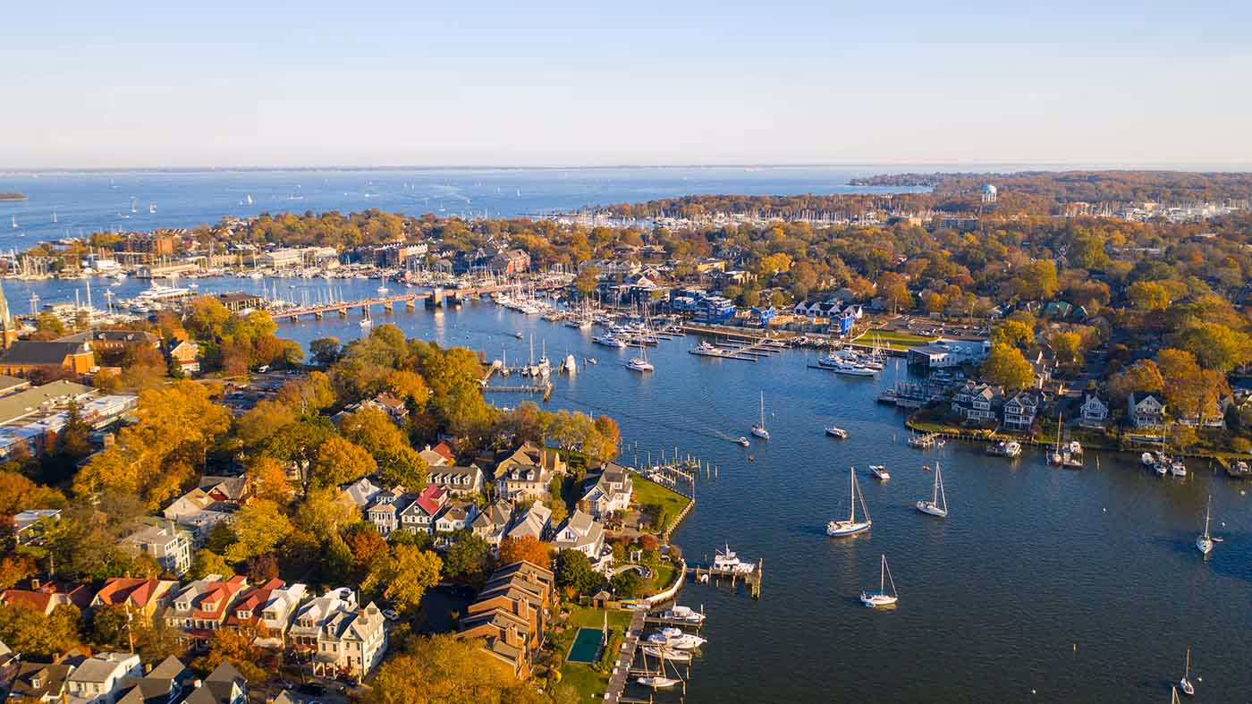 Aerial view of sailboats gliding through the calm waters of the Chesapeake Bay surrounded by golden autumn foliage