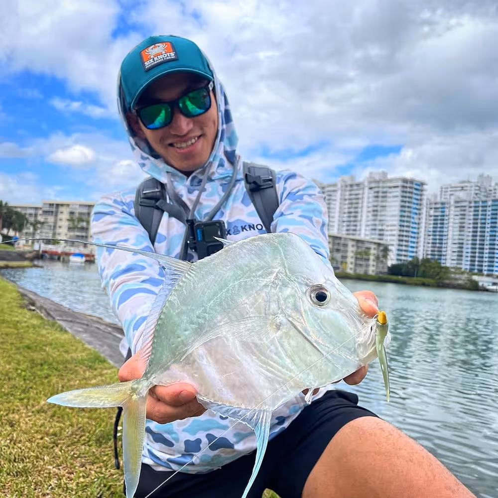 Ben proudly showing off his catch, dressed in a Six Knots Performance Hoodie and branded hat.