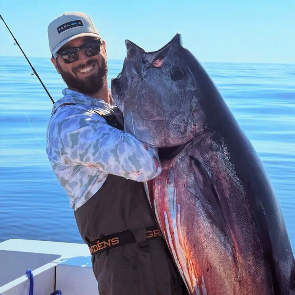 Reel Z Fishing poses with an enormous tuna catch, proudly dressed in a Six Knots Performance Hoodie on deck.